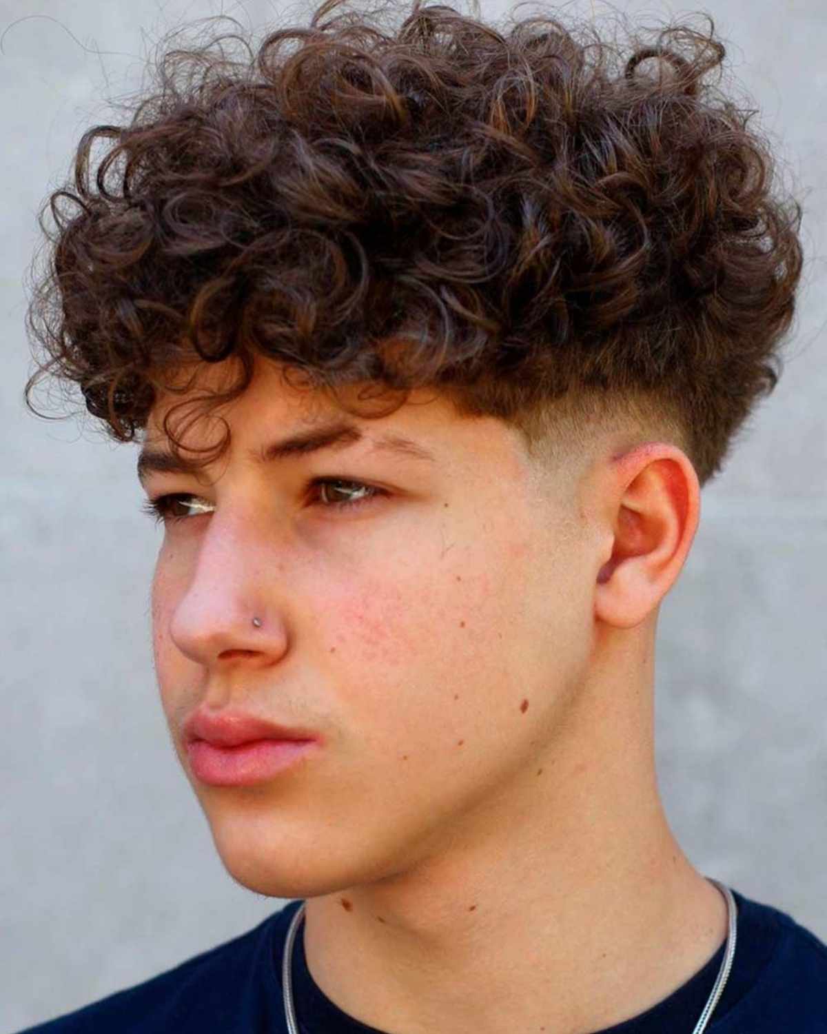 A curly quiff haircut showing natural curl definition at the front.