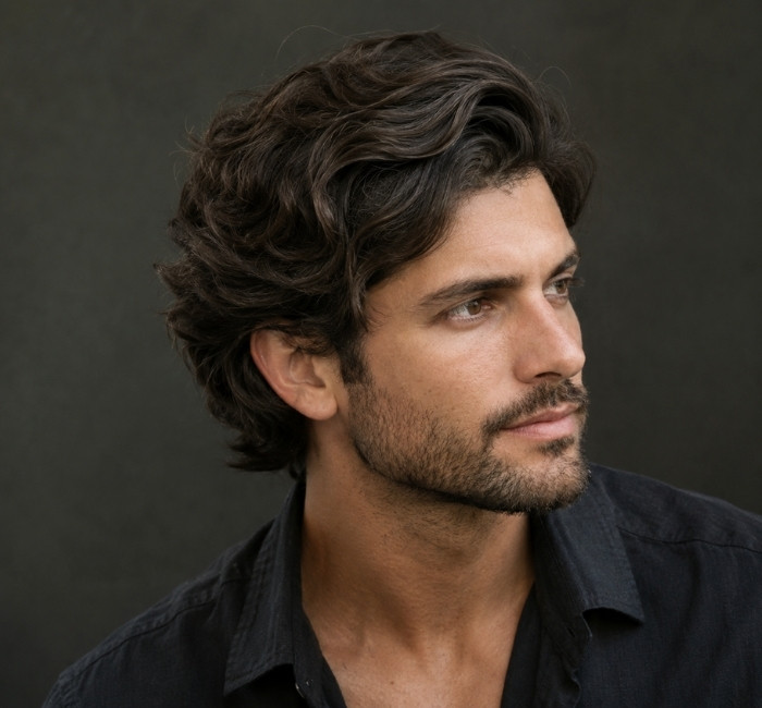 Layered wavy haircut for men with soft layers that boost wave definition and natural movement
